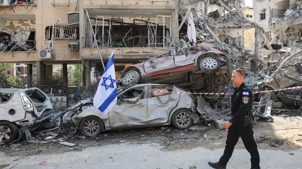 Policial caminha em frente a prédio e veículos destruídos por ataque do Irã à cidade de Ramat Gan, em Israel — Foto: REUTERS/Ronen Zvulun